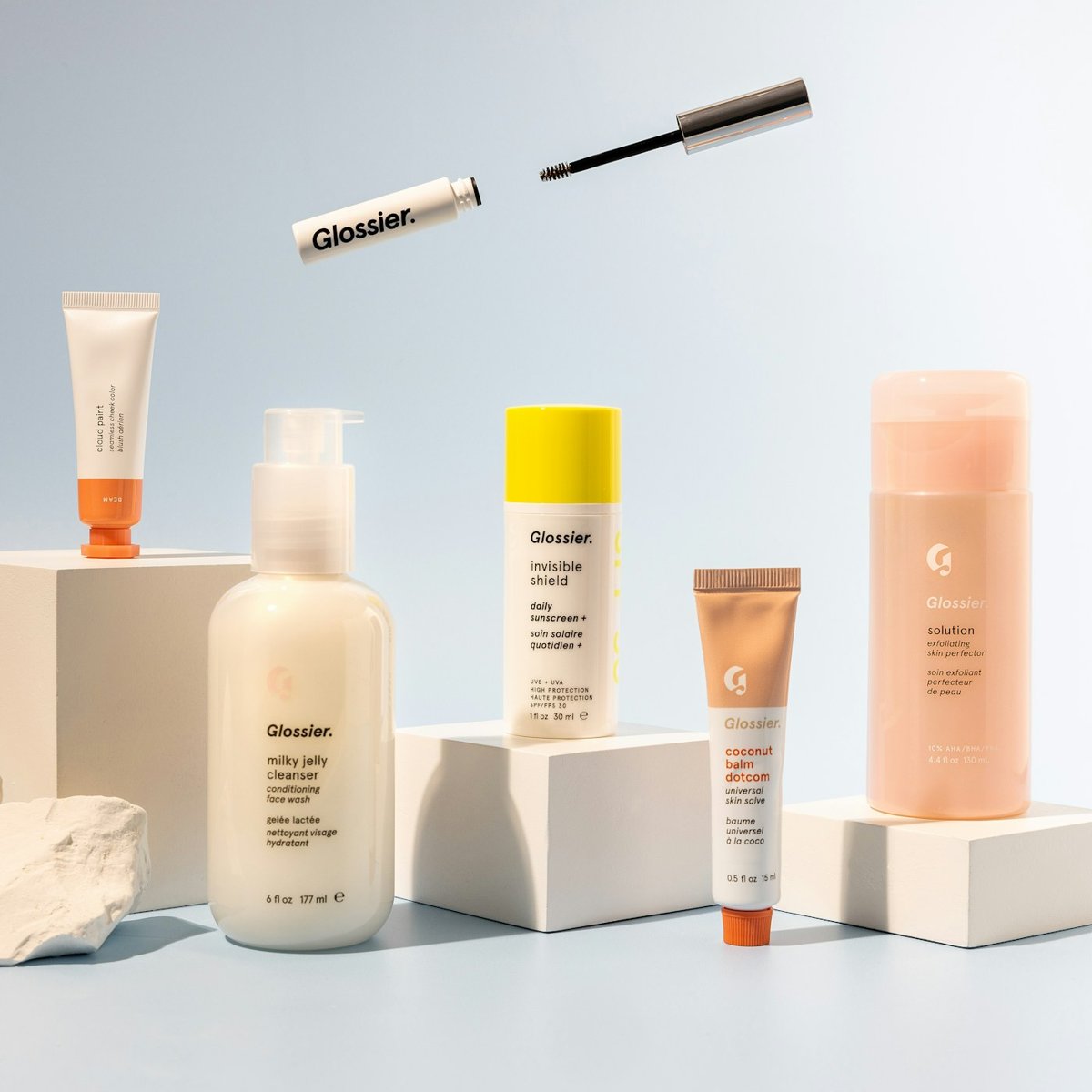 Skincare bottles on white pedestals against blue