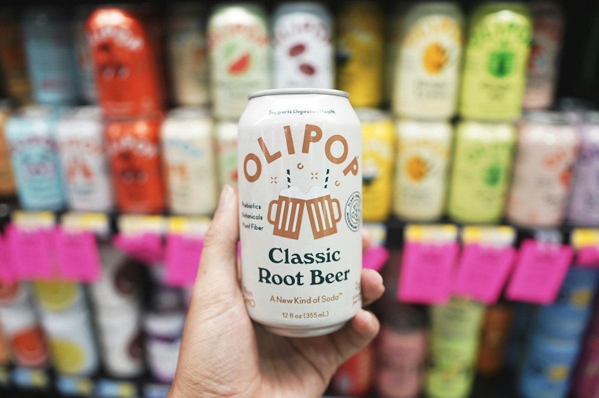 A hand holding an Olipop can in a store