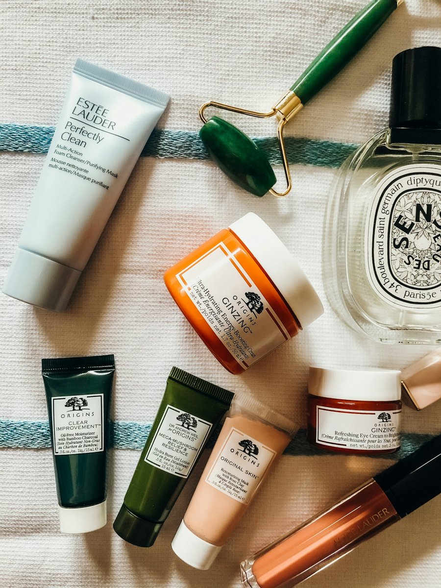 Skincare products and a jade roller on a towel