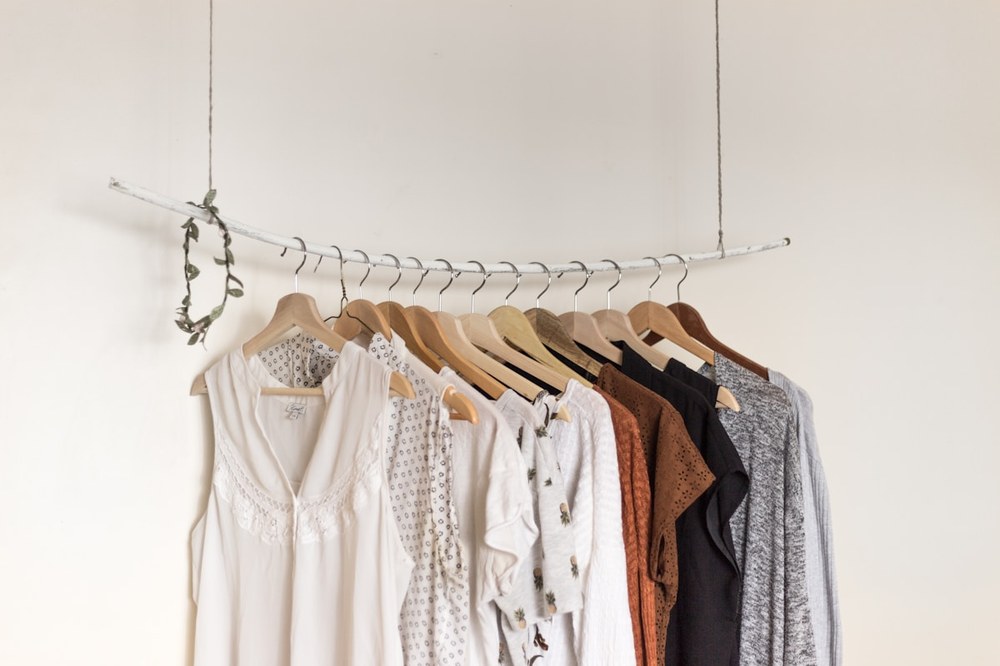 A rail of clothes on wooden hangers