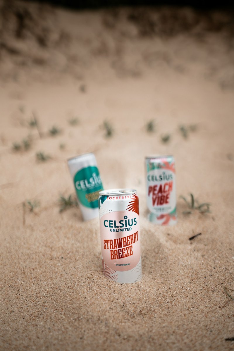 Three Celsius cans in the sand